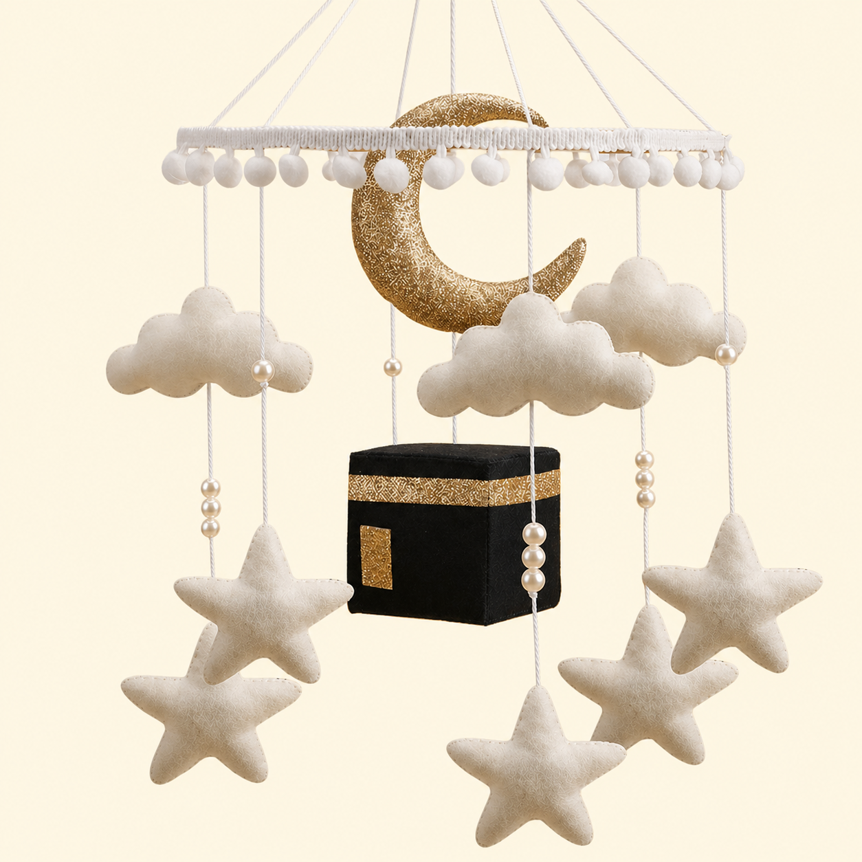 Decorative hanging mobile with clouds, stars, and a black cube on a beige background