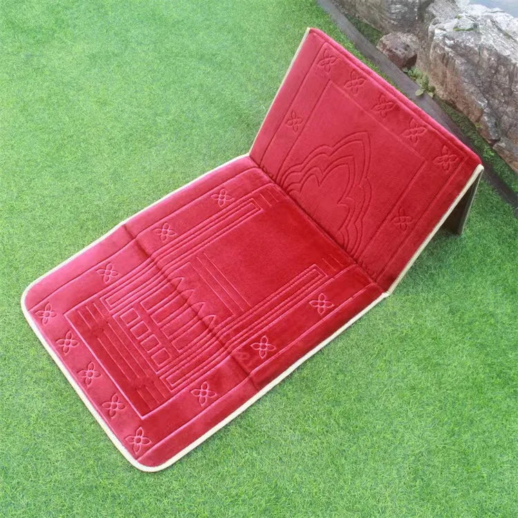 Red soft memory foam Islamic prayer mat with back rest and intricate patterns on a green grass background