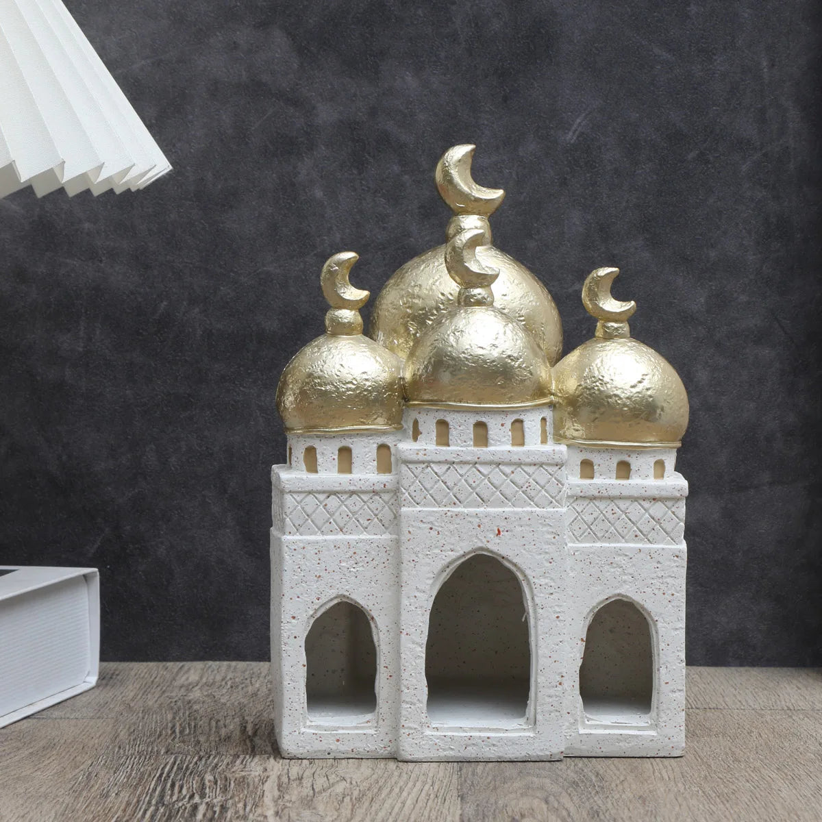 Decorative miniature model of a mosque with gold domes on a dark background