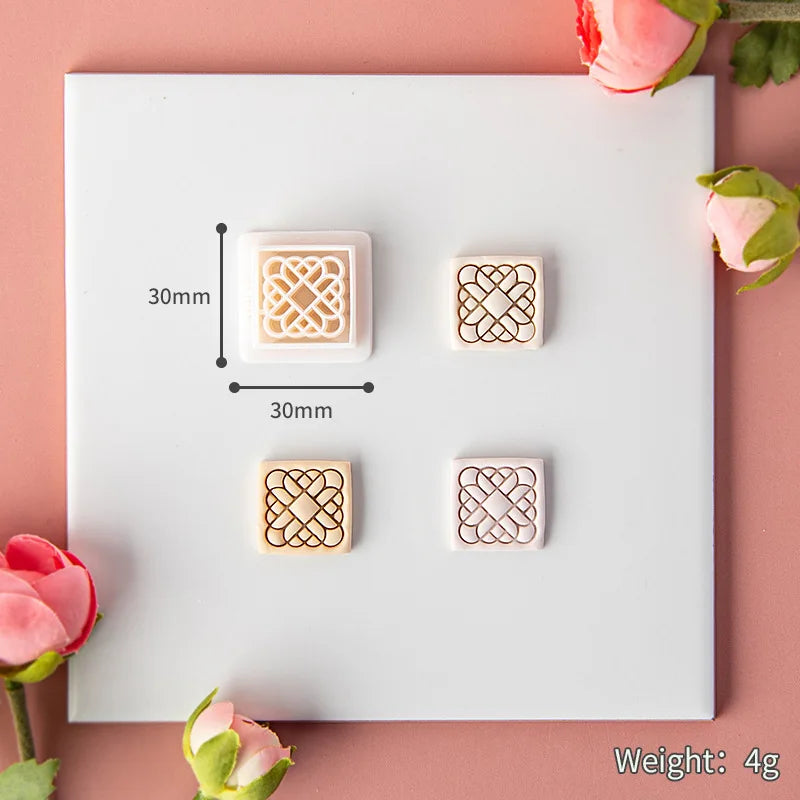 Wooden stamp set with geometric designs on a white card, surrounded by pink flowers.