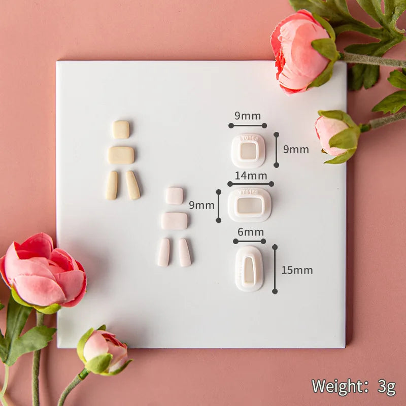 Set of small ceramic items with measurements on a white card, surrounded by pink flowers on a pink background.
