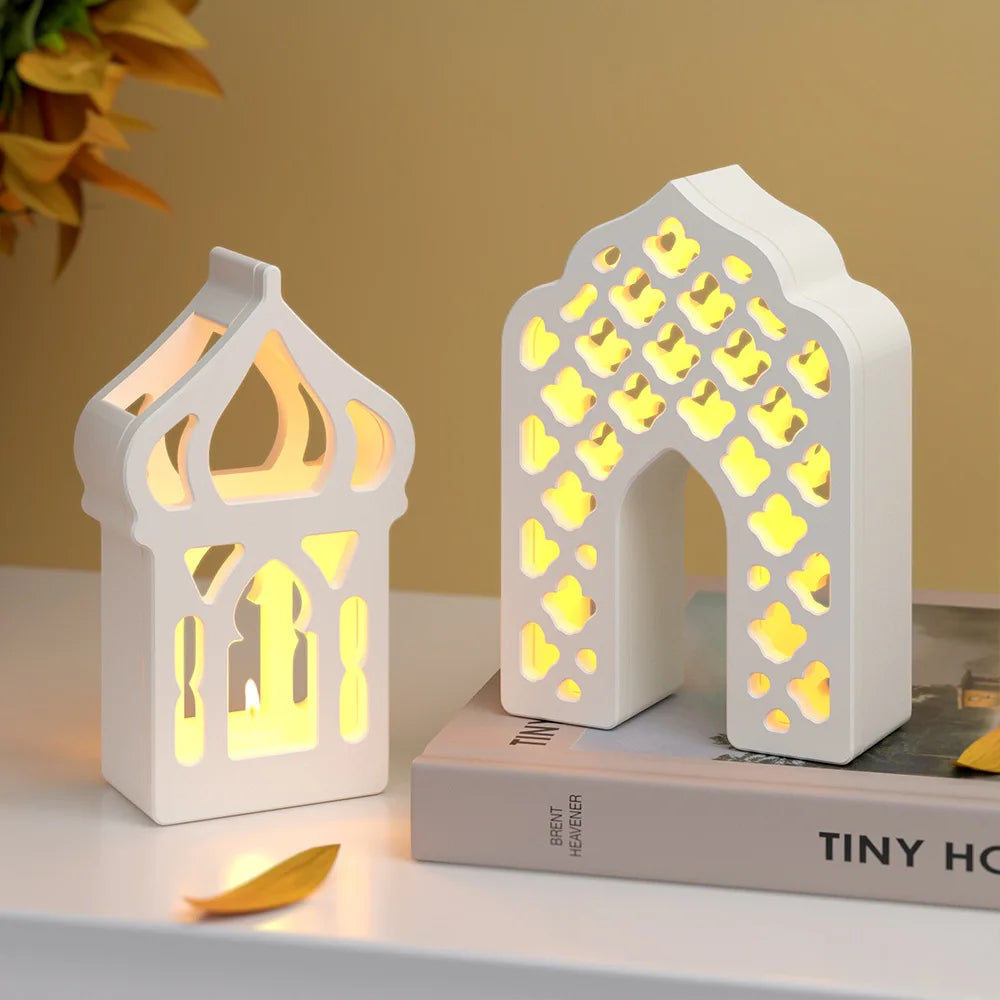 Two white Islamic decorative lanterns with cut-out patterns on a surface.