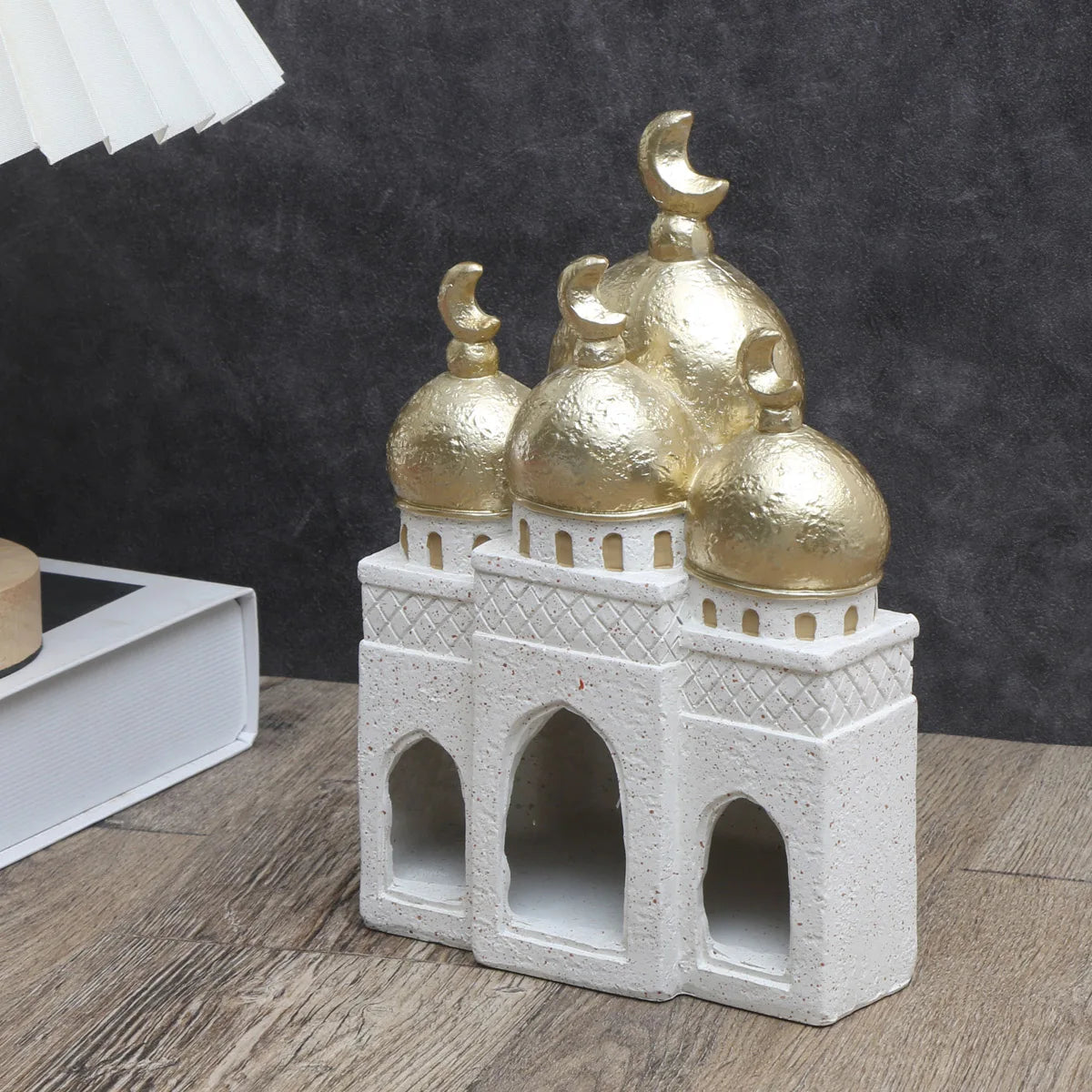 Decorative miniature mosque with gold domes on a wooden surface