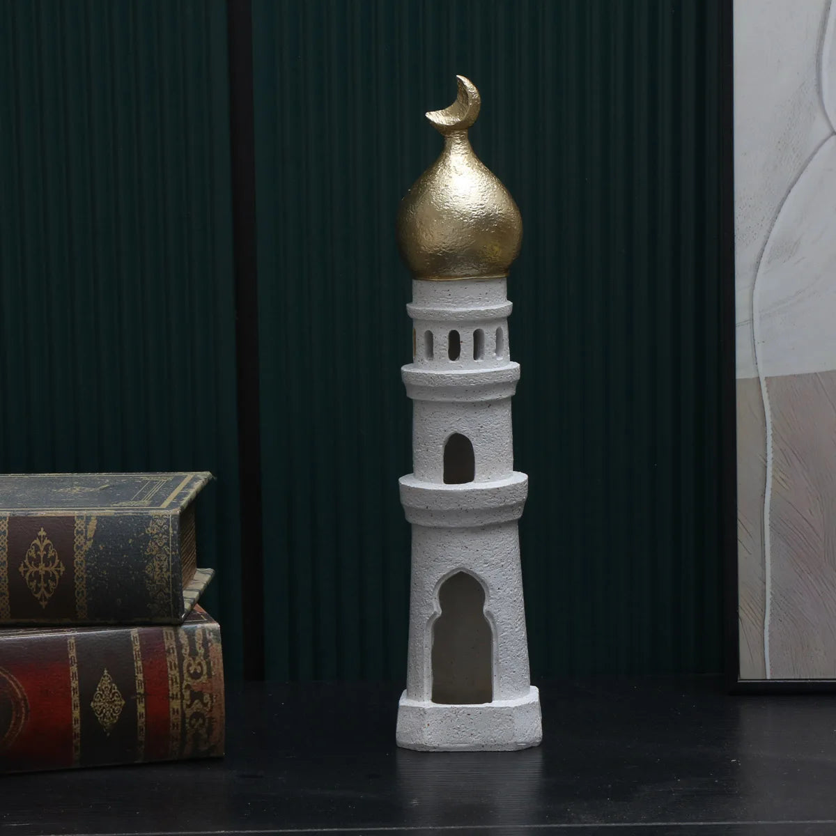 Decorative tower with gold dome and white base on a dark surface