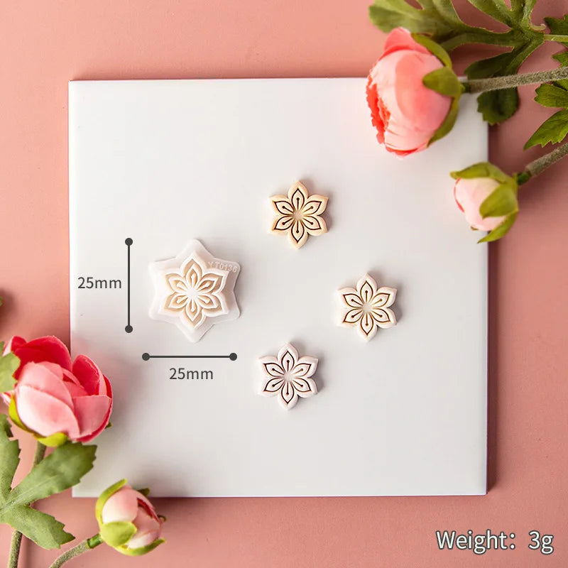 Floral earrings on a white card with measurements and weight information, surrounded by pink flowers on a pink background.