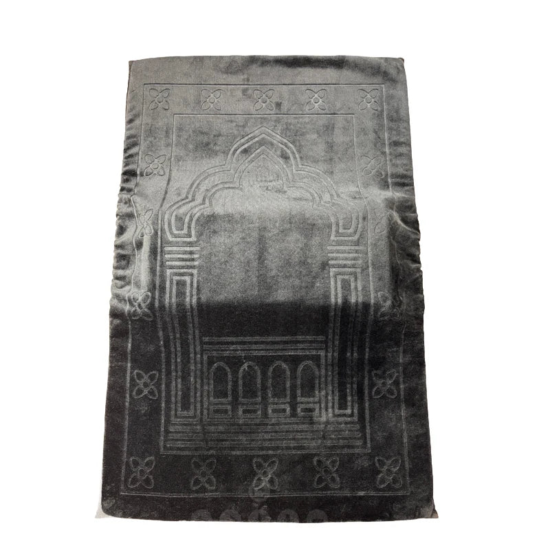 Black prayer mat with geometric patterns on a white background