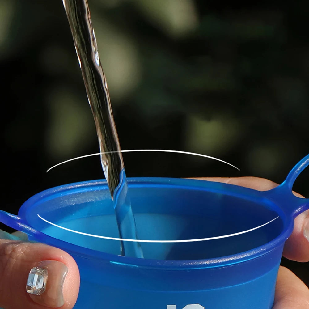 Blue portable cup being filled with water against a blurred natural background
