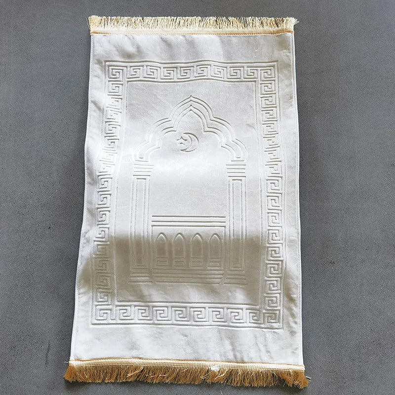 White prayer mat with gold fringe on a gray background