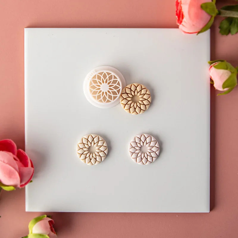 Decorative mold cutters with floral designs on a white square background, surrounded by pink flowers.