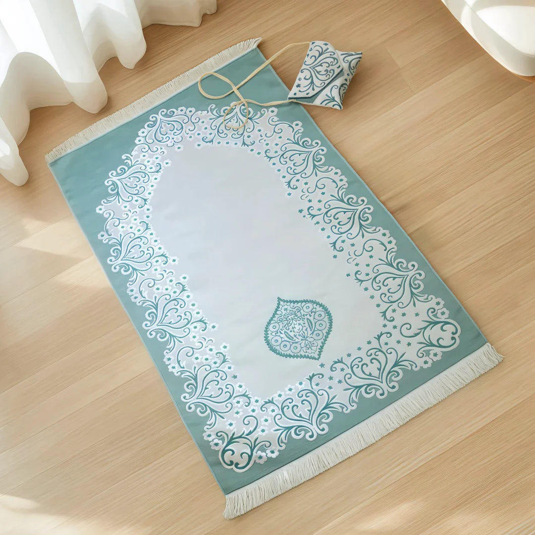 Decorative teal Islamic prayer rug with white patterns on a wooden floor