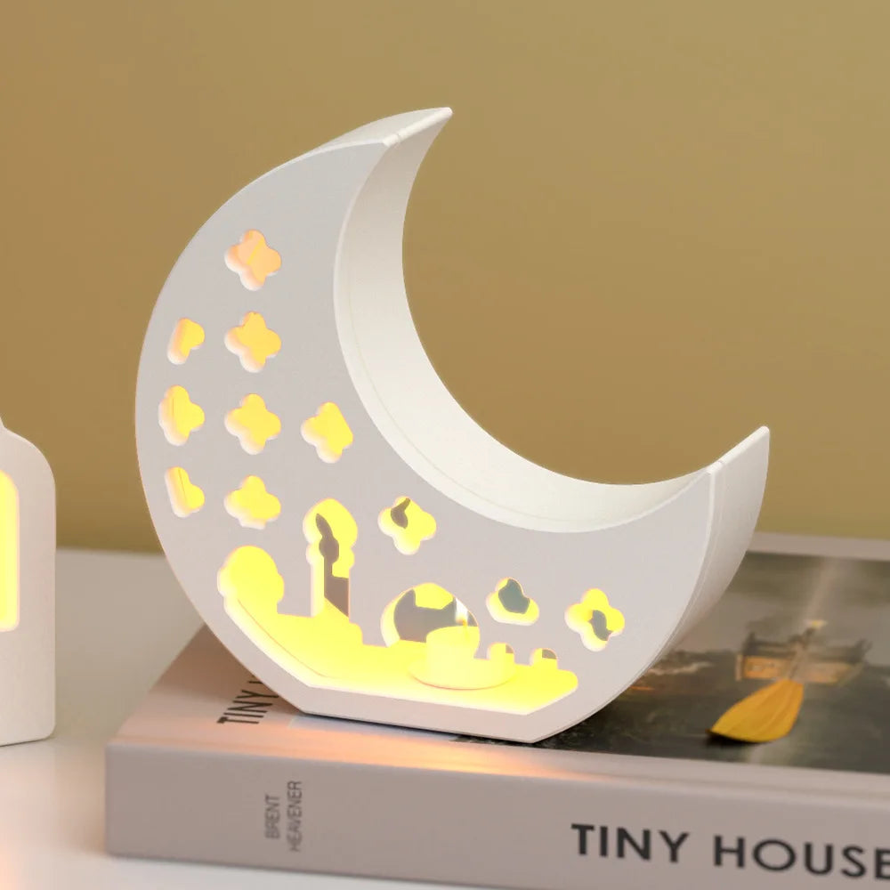 Moon-shaped night light with cut-out designs on a book against a beige background