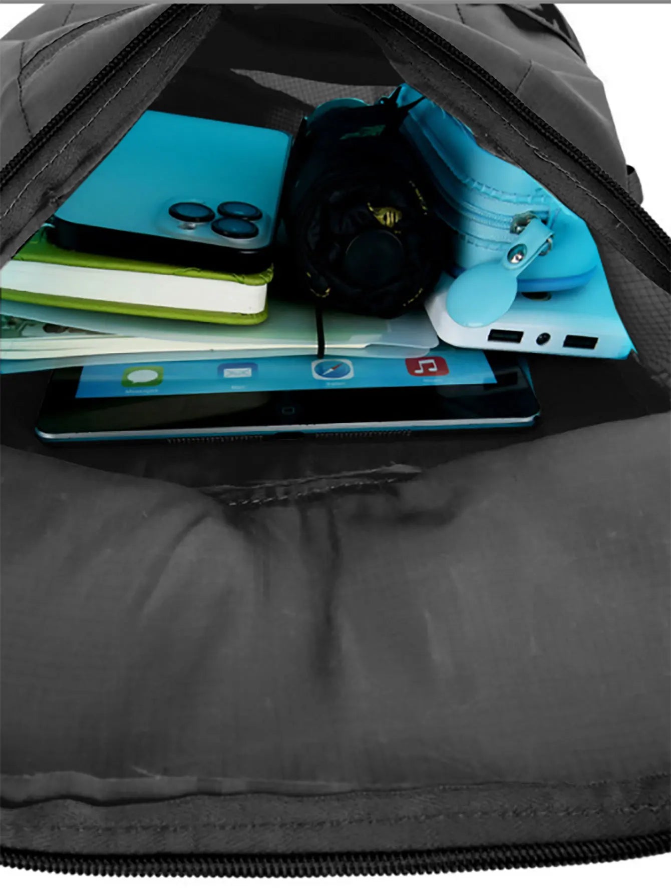Black backpack with items including a blue phone, green notebook, and black helmet. for hajj and umrah pilgrimage