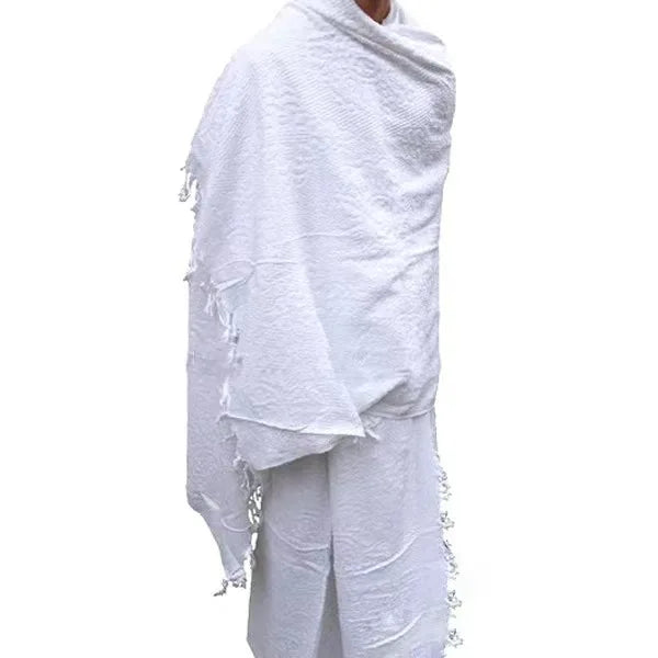 White ihram for hajj and umrah pilgrims with fringe details draped over a person on a white background