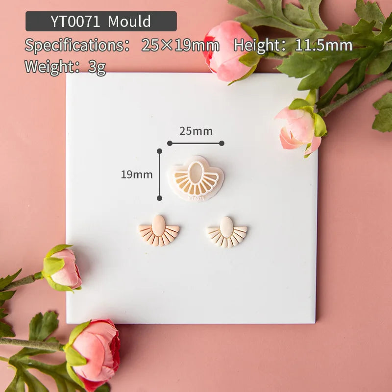 Mould with earrings on a white card, surrounded by pink flowers and green leaves on a pink background.