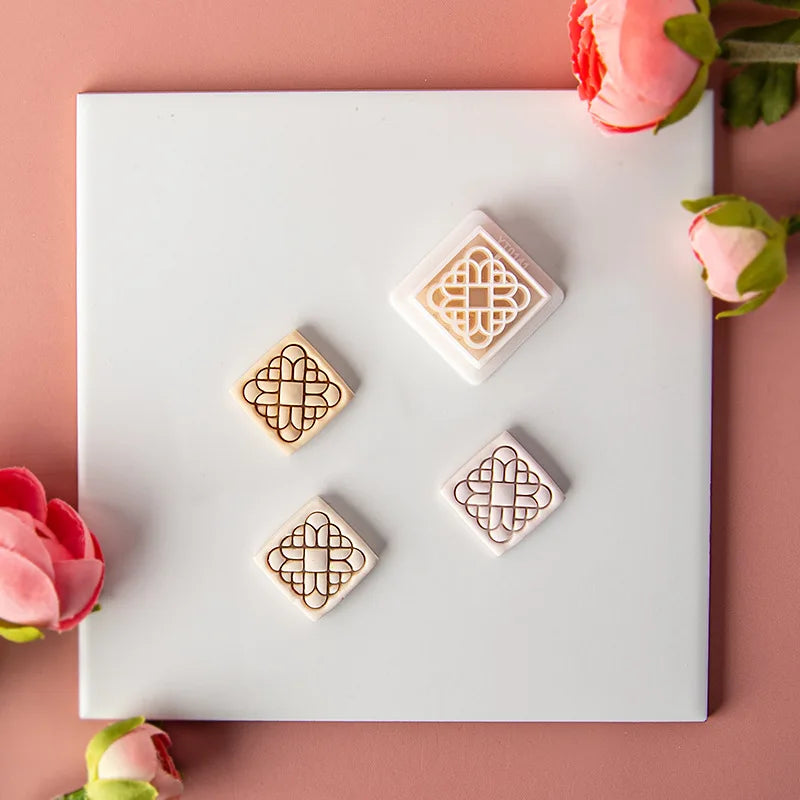 Wooden stamp set with geometric designs on a white card, surrounded by pink flowers.
