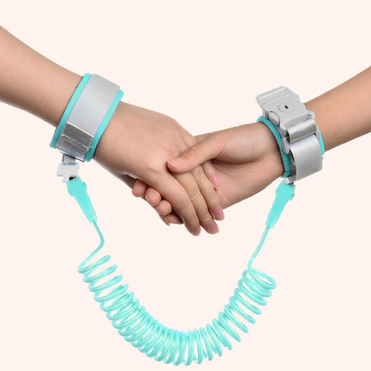 Two hands holding together with a turquoise kids safety leashes on a white background