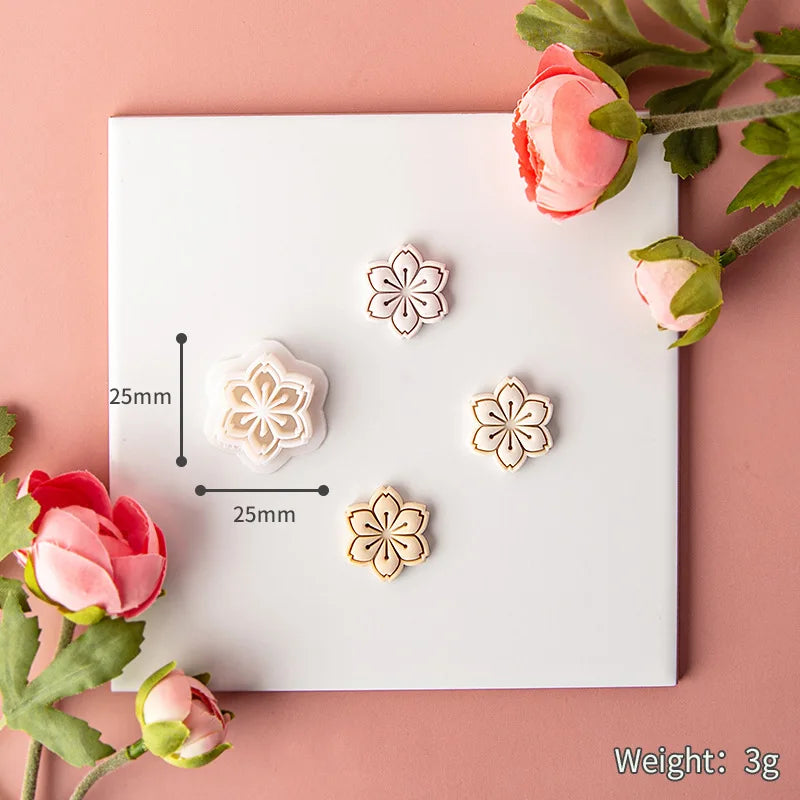 Floral clay mold on a white card with measurements and weight information, surrounded by pink flowers on a pink background.