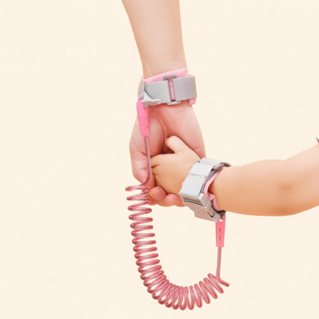 Pink and gray child leash with a hand holding it against a light beige background