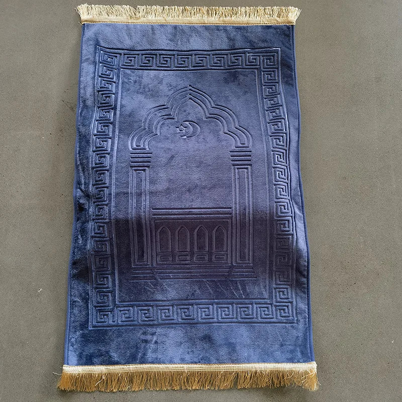Blue prayer mat with gold fringes on a gray background