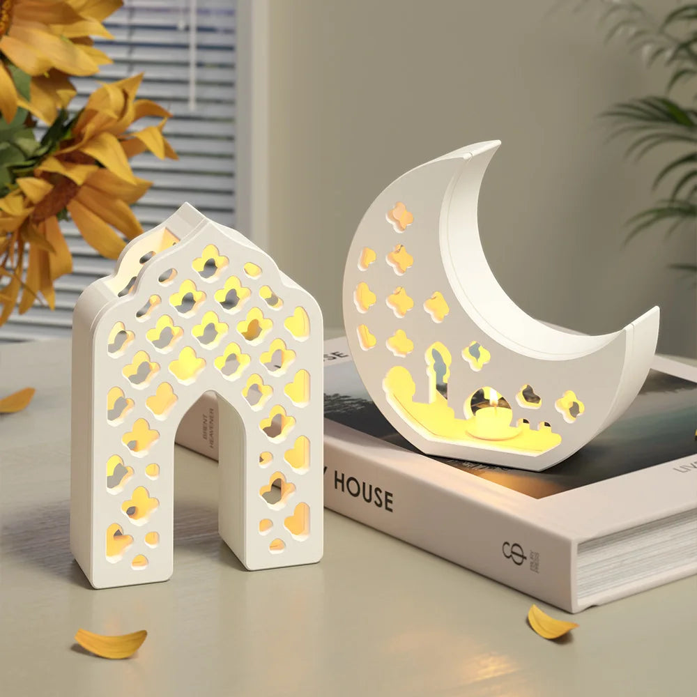 Decorative night lights shaped like a house and a crescent moon on books with a blurred indoor background.